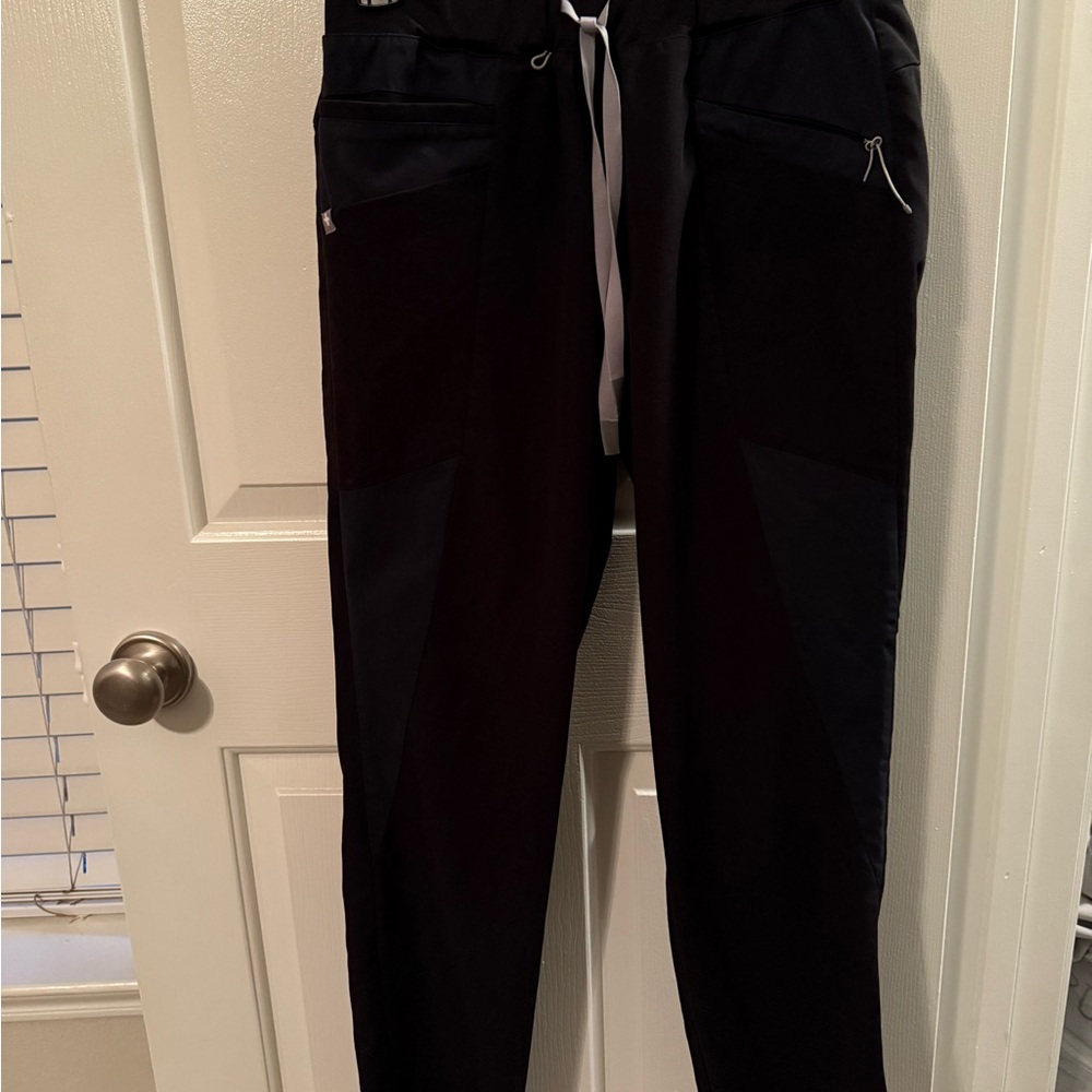 Figs Mombasa black scrub pants with navy mesh accents.